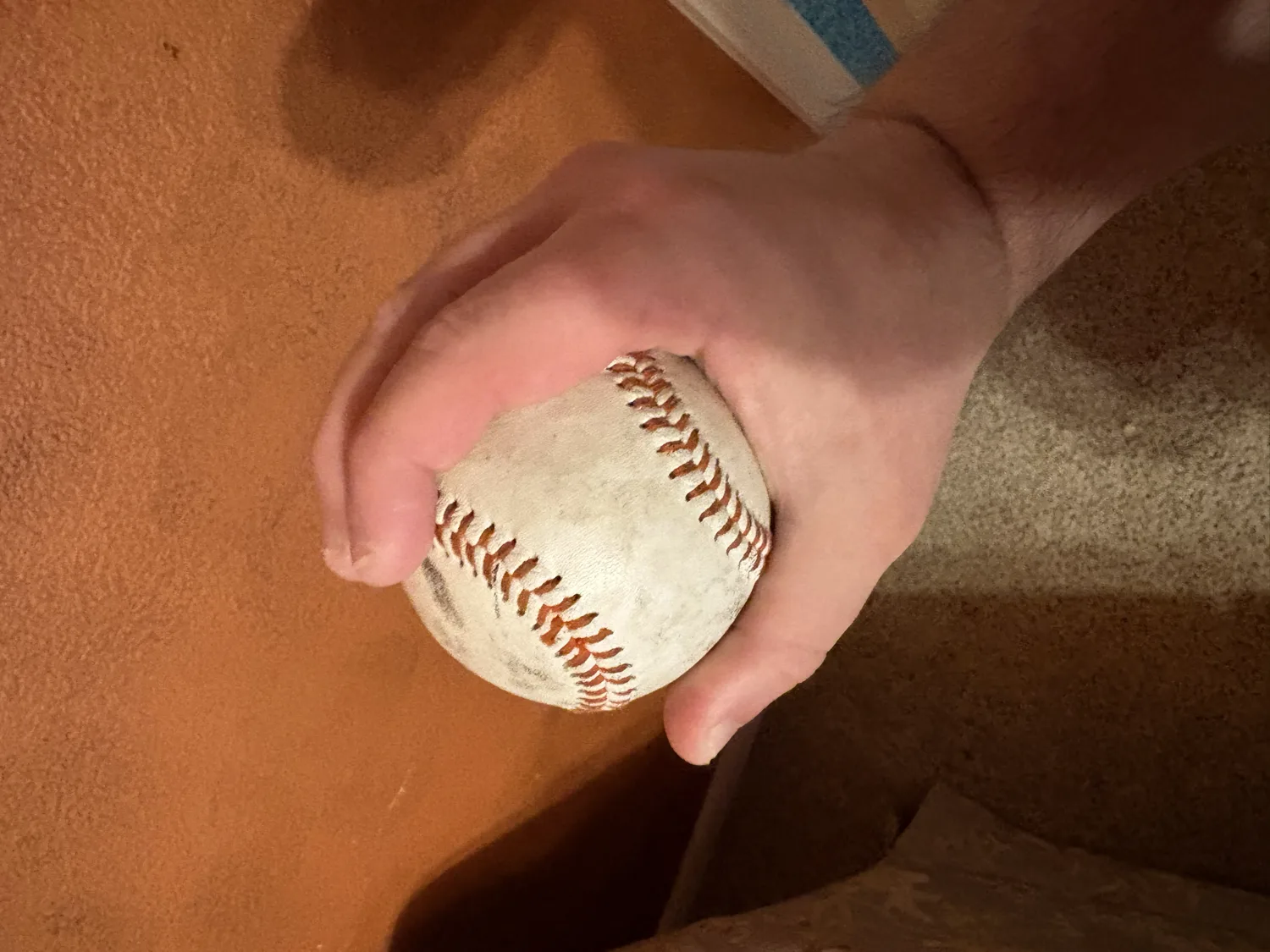 A side view of a football changeup grip with the ball set deep in the hand under four fingers.