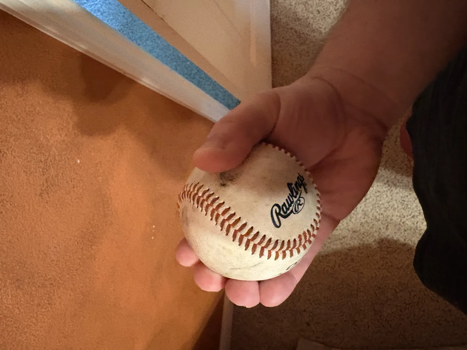 A hand gripping a baseball with all four fingers together across the top, the football changeup grip.
