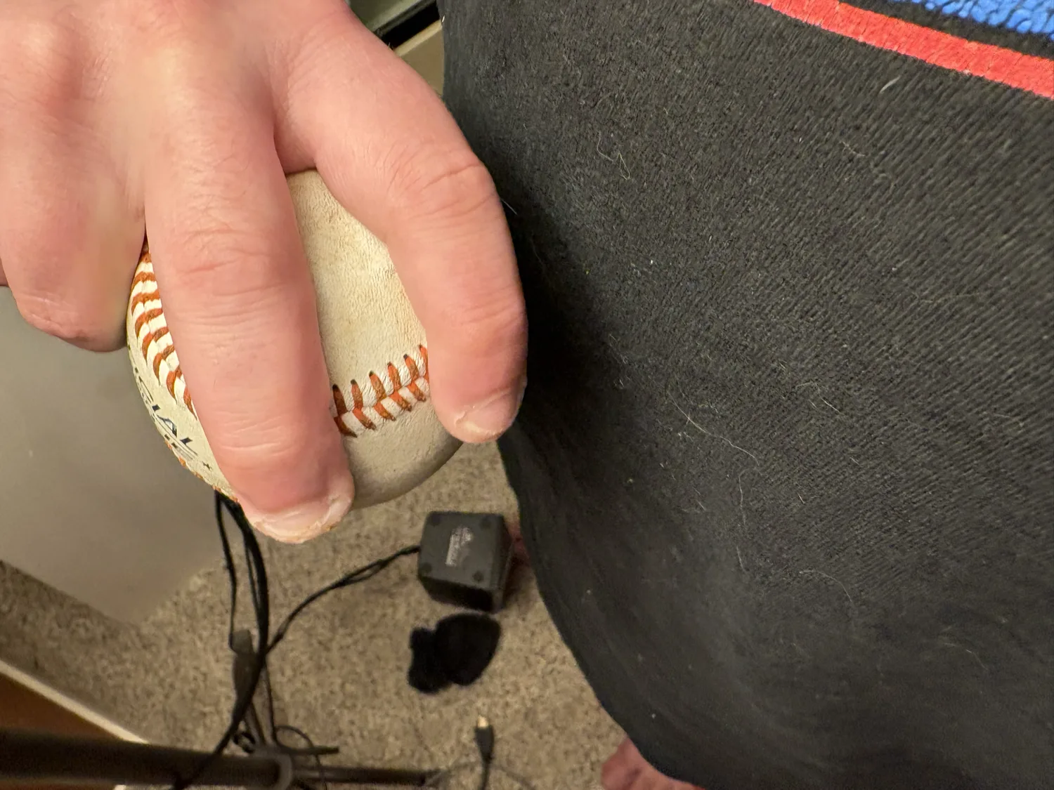 A side view of a four-seam fastball grip, fingertips crossing the seam.