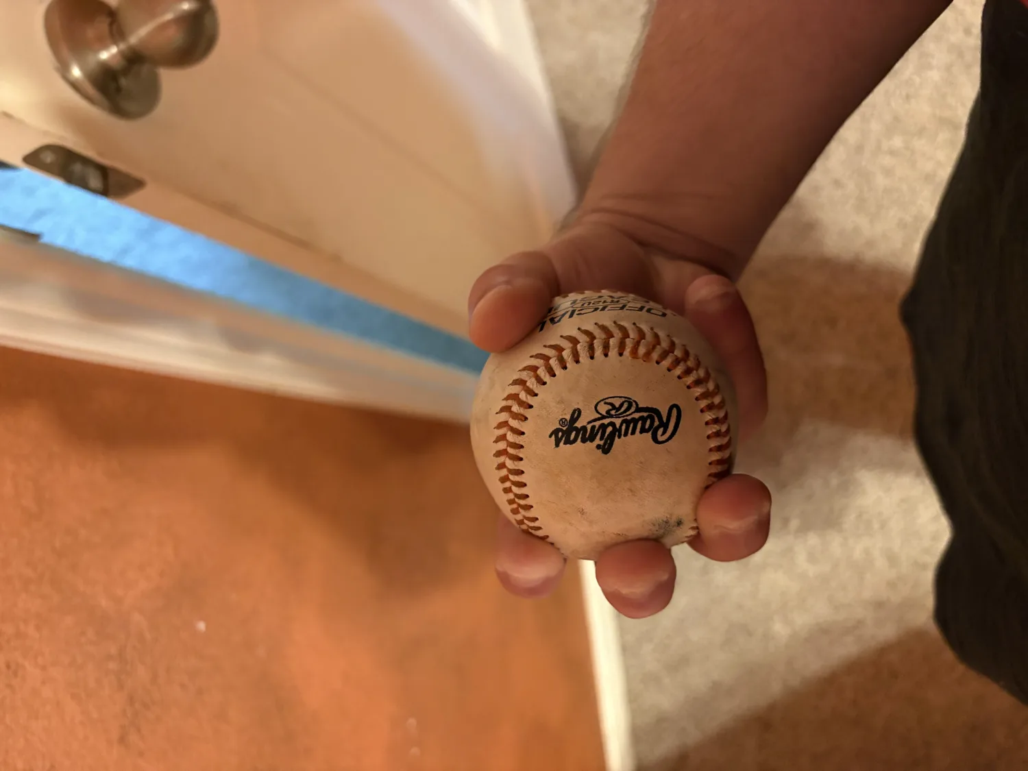 A hand gripping a baseball with three fingers close together across the top, a three-finger changeup grip.
