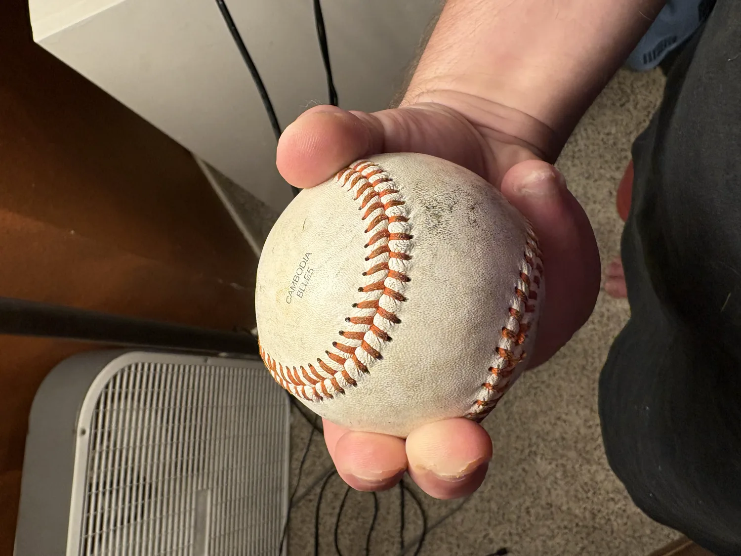 A hand gripping a baseball for a 12-6 curveball, two fingers together cornered against one seam.