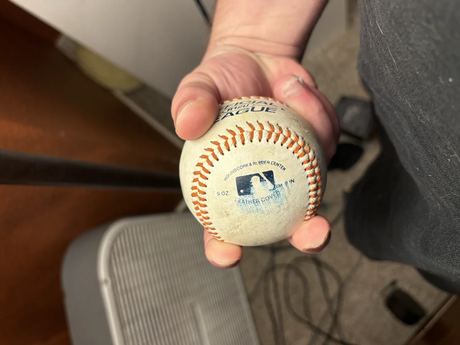 A hand gripping a baseball two-seam style, index and middle fingers running along the two narrow parallel seams.